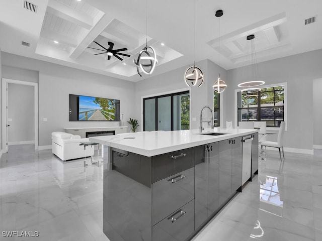 kitchen featuring an island with sink, sink, gray cabinetry, decorative light fixtures, and coffered ceiling