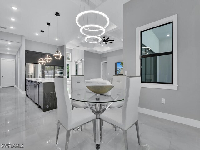 dining room featuring ceiling fan with notable chandelier, coffered ceiling, sink, and a barn door