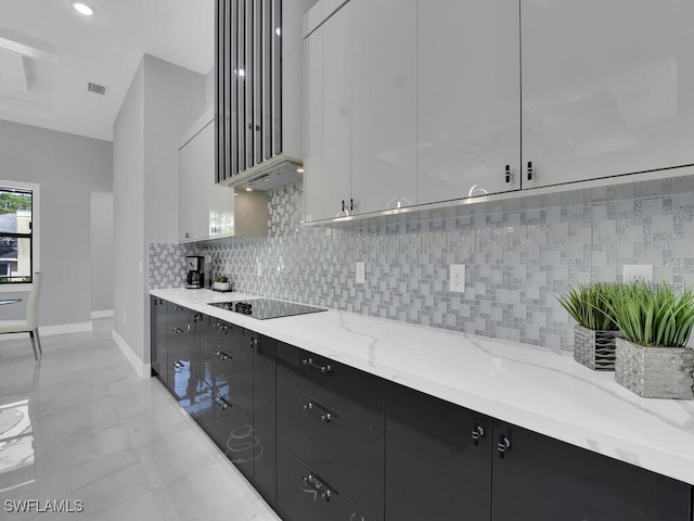 kitchen featuring black electric cooktop, white cabinets, light stone countertops, and tasteful backsplash