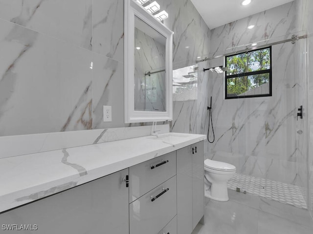 bathroom with toilet, vanity, a tile shower, and tile walls