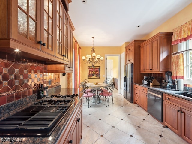 kitchen featuring an inviting chandelier, backsplash, dark stone countertops, pendant lighting, and black appliances