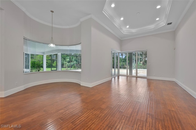 unfurnished living room featuring crown molding, a towering ceiling, and hardwood / wood-style floors