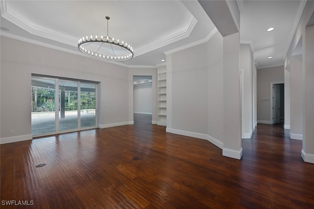 spare room with a chandelier, a raised ceiling, crown molding, dark hardwood / wood-style floors, and built in features