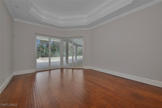 empty room featuring a raised ceiling, hardwood / wood-style floors, and ornamental molding