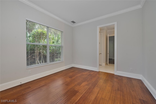 empty room with hardwood / wood-style floors and crown molding