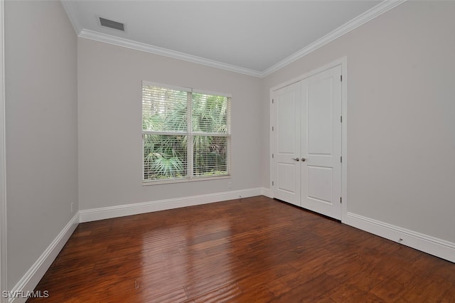 empty room with dark hardwood / wood-style flooring and crown molding