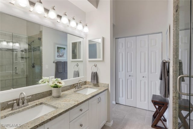 bathroom with a shower with door, vanity, and tile patterned flooring