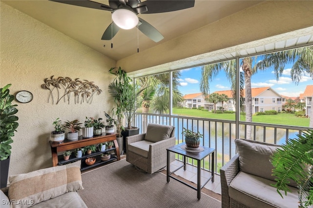 sunroom with lofted ceiling, a water view, and ceiling fan