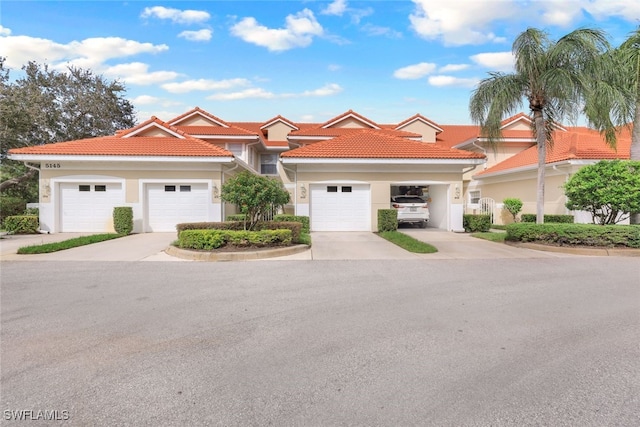 view of front of home featuring concrete driveway, a tiled roof, and stucco siding