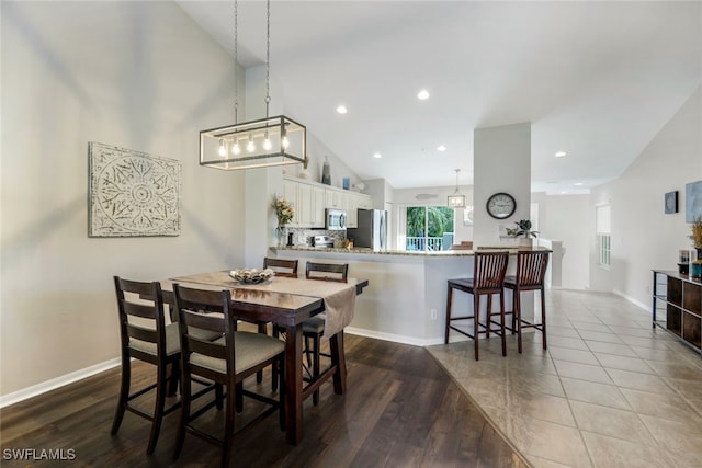 dining room with wood-type flooring and high vaulted ceiling