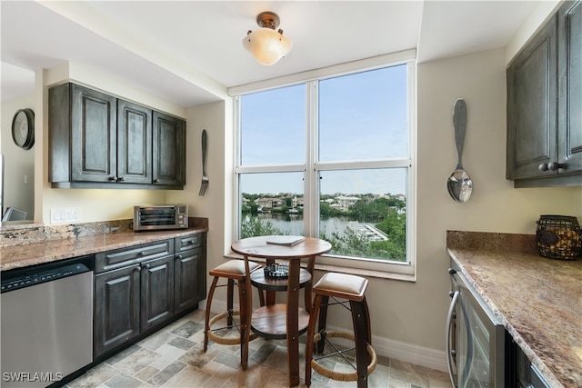 kitchen featuring a water view, light stone counters, appliances with stainless steel finishes, and dark brown cabinetry