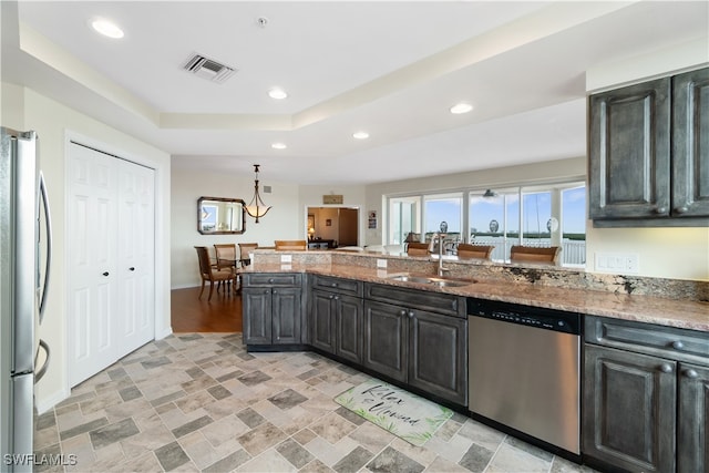 kitchen featuring light stone countertops, sink, appliances with stainless steel finishes, and a raised ceiling