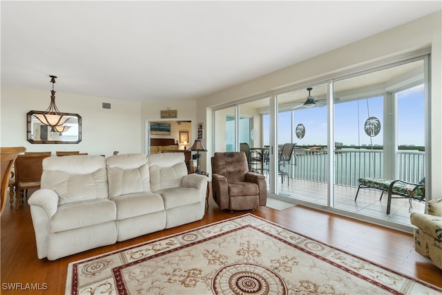 living room featuring hardwood / wood-style floors, a water view, and ceiling fan