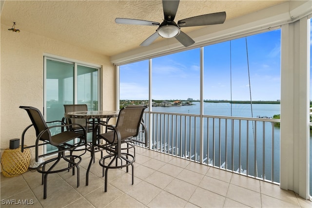 sunroom with a water view and ceiling fan