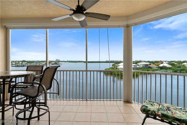 sunroom with a water view and ceiling fan