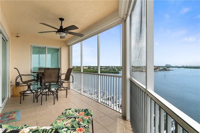 sunroom with a water view and ceiling fan