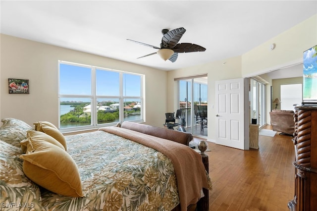 bedroom featuring dark hardwood / wood-style flooring, multiple windows, a water view, and ceiling fan