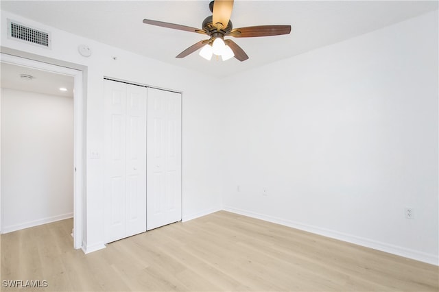 unfurnished bedroom featuring a closet, light hardwood / wood-style flooring, and ceiling fan