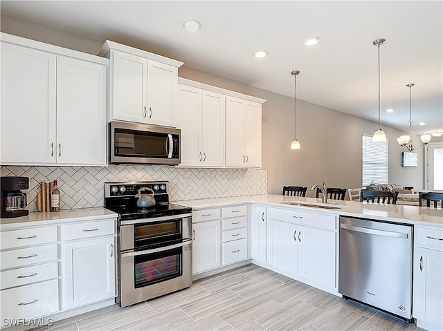 kitchen with white cabinetry, sink, hanging light fixtures, decorative backsplash, and appliances with stainless steel finishes