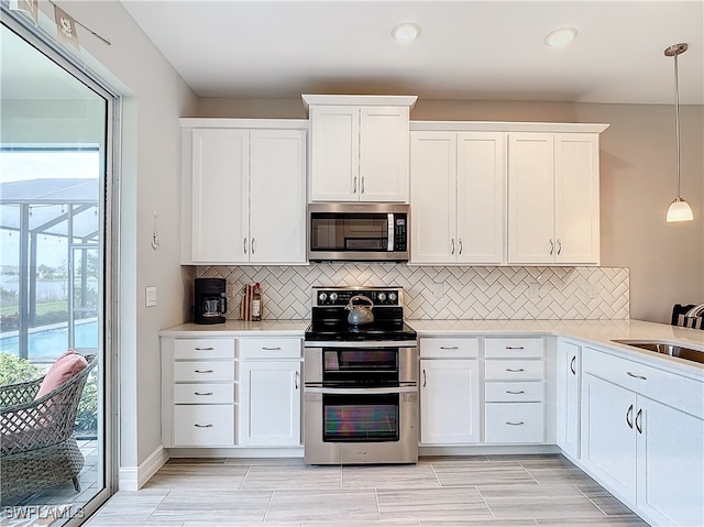 kitchen with sink, hanging light fixtures, decorative backsplash, white cabinetry, and stainless steel appliances