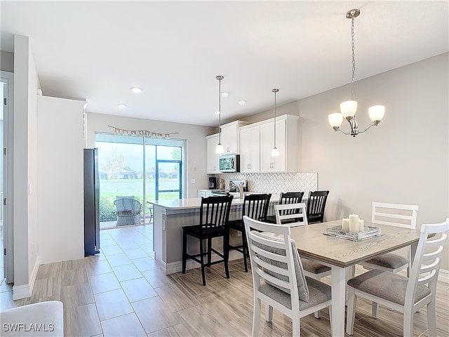 dining area with light hardwood / wood-style flooring and a notable chandelier