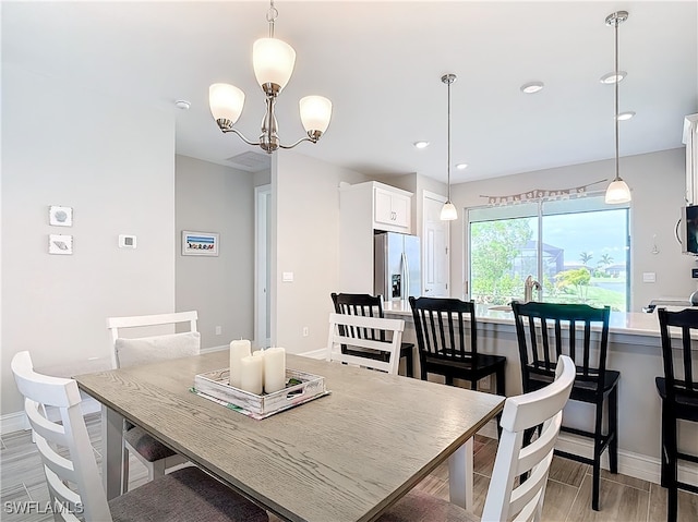 dining area with an inviting chandelier and light hardwood / wood-style flooring