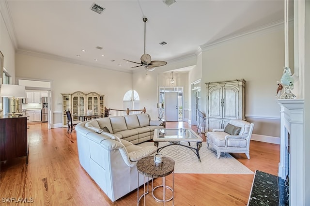 living room with crown molding, light hardwood / wood-style floors, and ceiling fan