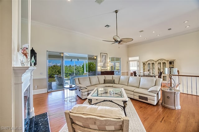 living room with ceiling fan, light wood-type flooring, and crown molding