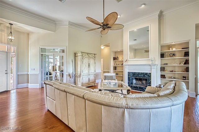 living room with ornamental molding, a high end fireplace, ceiling fan, and hardwood / wood-style flooring