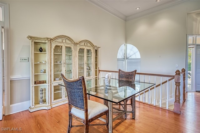 dining room with wood-type flooring, plenty of natural light, crown molding, and a towering ceiling