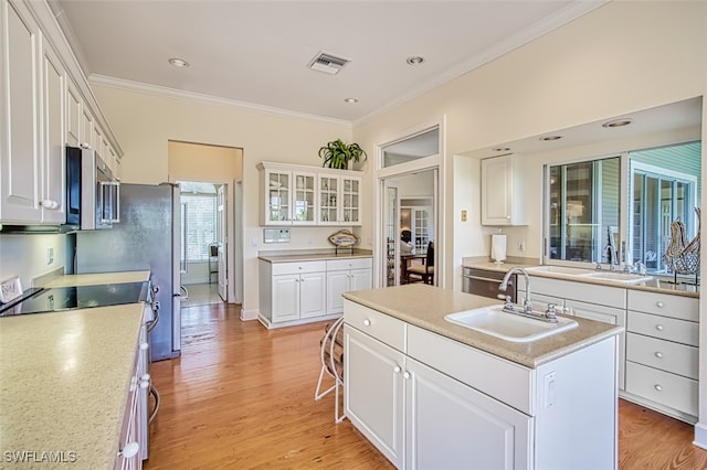 kitchen featuring a center island with sink, white cabinetry, sink, and stainless steel appliances