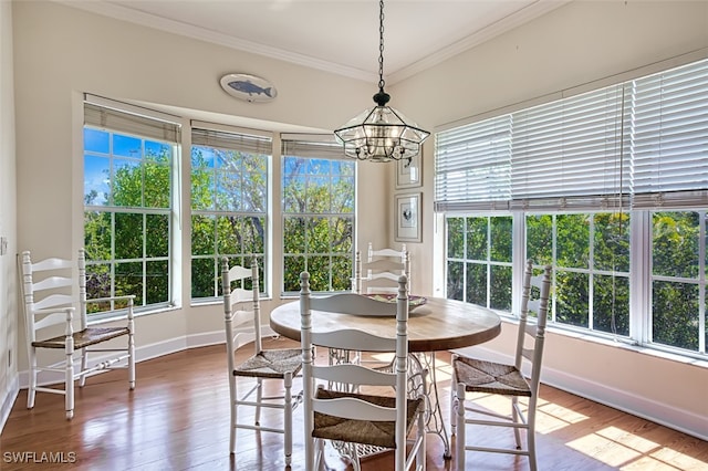 dining area with wood-type flooring, crown molding, a chandelier, and a healthy amount of sunlight