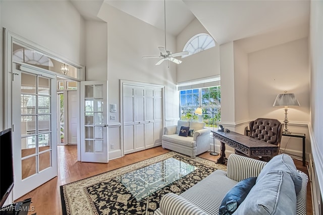 living room with wood-type flooring, ceiling fan, and high vaulted ceiling