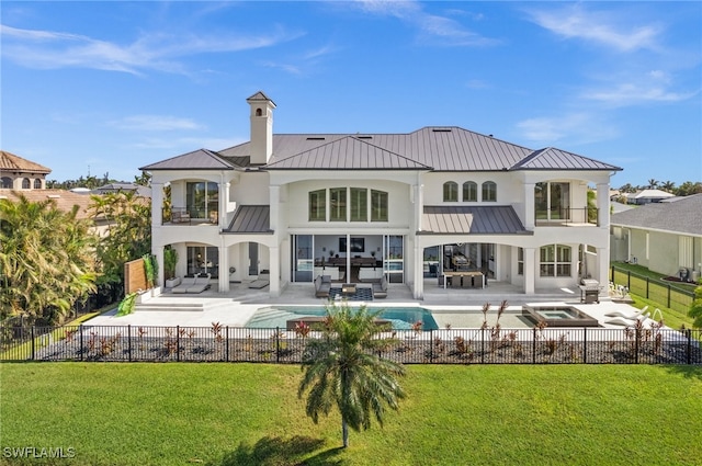 rear view of property with a balcony, a swimming pool with hot tub, a yard, an outdoor living space, and a patio area