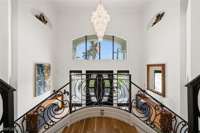 stairs with hardwood / wood-style flooring, ornamental molding, and a notable chandelier