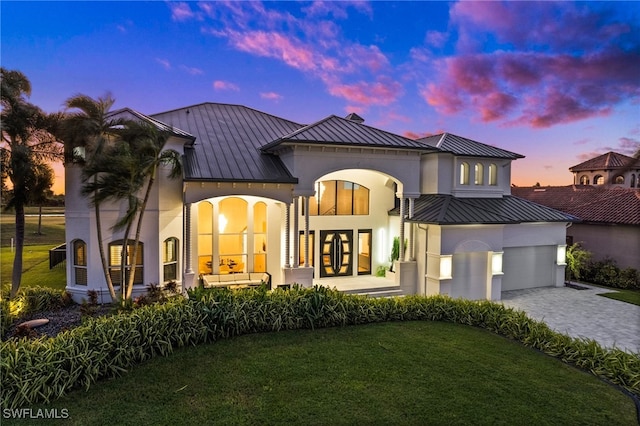 view of front of home featuring french doors, a garage, and a lawn