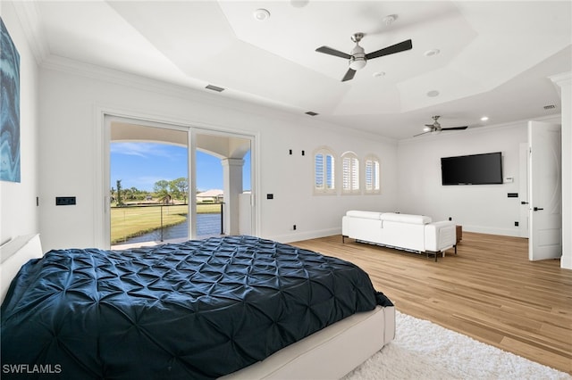 bedroom featuring crown molding, ceiling fan, access to exterior, a raised ceiling, and light wood-type flooring