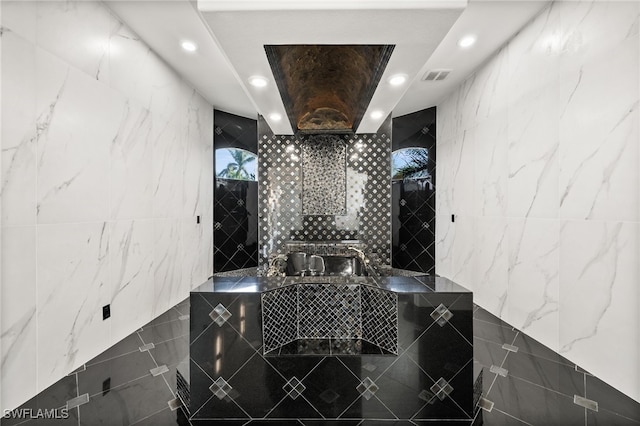 bathroom with walk in shower, a raised ceiling, and tile walls