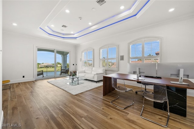 office area with crown molding, a tray ceiling, and light hardwood / wood-style floors