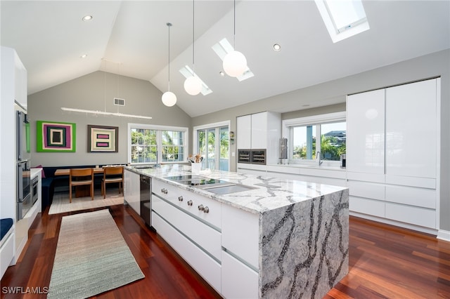 kitchen with a large island, a healthy amount of sunlight, a skylight, and white cabinets