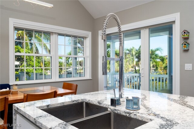 interior space featuring lofted ceiling, light stone countertops, and sink