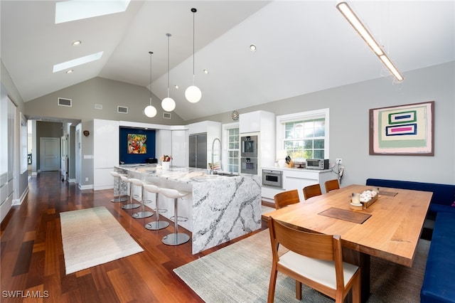 dining area with dark hardwood / wood-style floors, sink, high vaulted ceiling, and a skylight