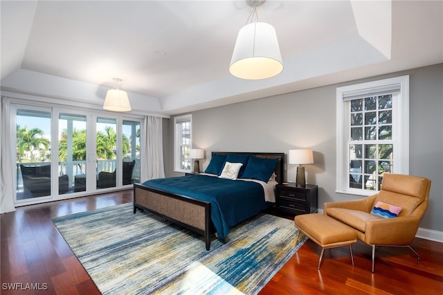 bedroom with access to outside, a raised ceiling, and dark hardwood / wood-style flooring