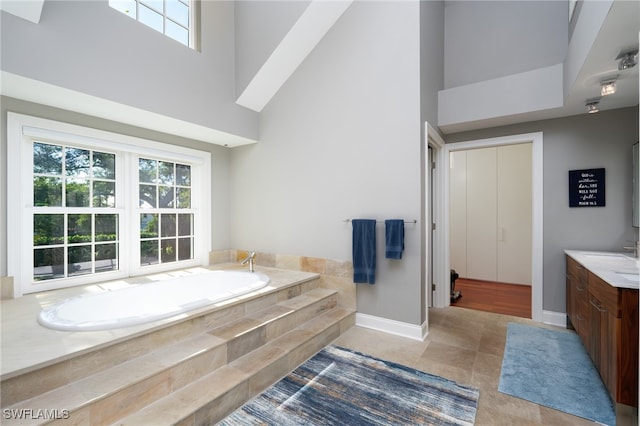 bathroom featuring vanity, a relaxing tiled tub, tile patterned floors, and a high ceiling