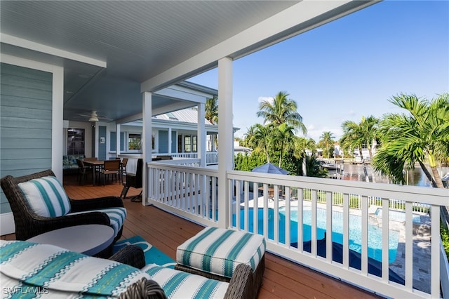 balcony featuring a deck with water view and ceiling fan