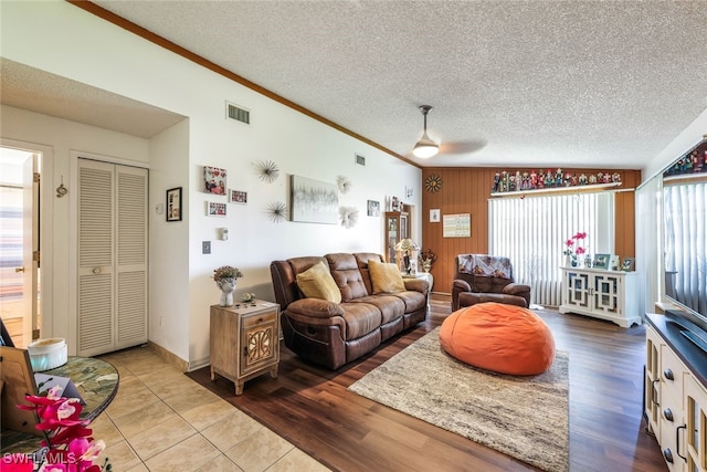 living room featuring ceiling fan, lofted ceiling, ornamental molding, a textured ceiling, and light hardwood / wood-style floors