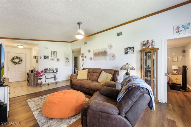 living room with a textured ceiling, wood-type flooring, and crown molding