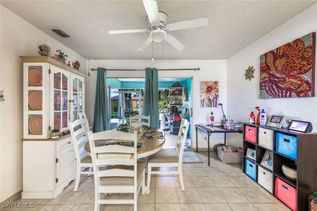 dining space with ceiling fan, light tile patterned floors, and a textured ceiling