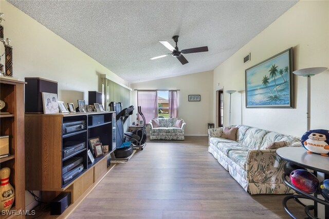 living room with vaulted ceiling, a textured ceiling, and hardwood / wood-style floors