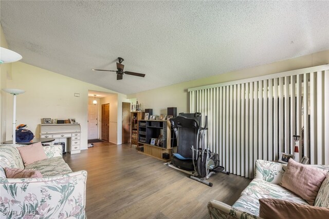 living room with a textured ceiling, lofted ceiling, ceiling fan, and dark wood-type flooring